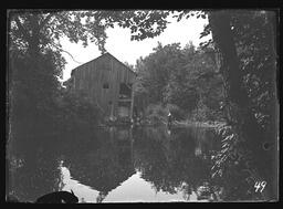[Wooden Building at Water's Edge with Woman Fishing]